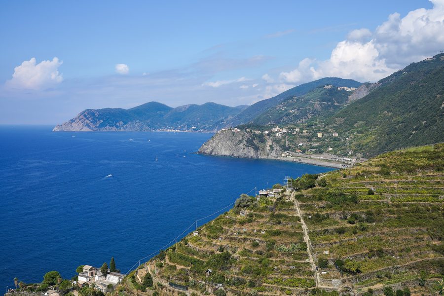 Vista ampia della costa delle Cinque Terre dall’alto di Manarola, con ripide colline sopra il Mar Ligure.