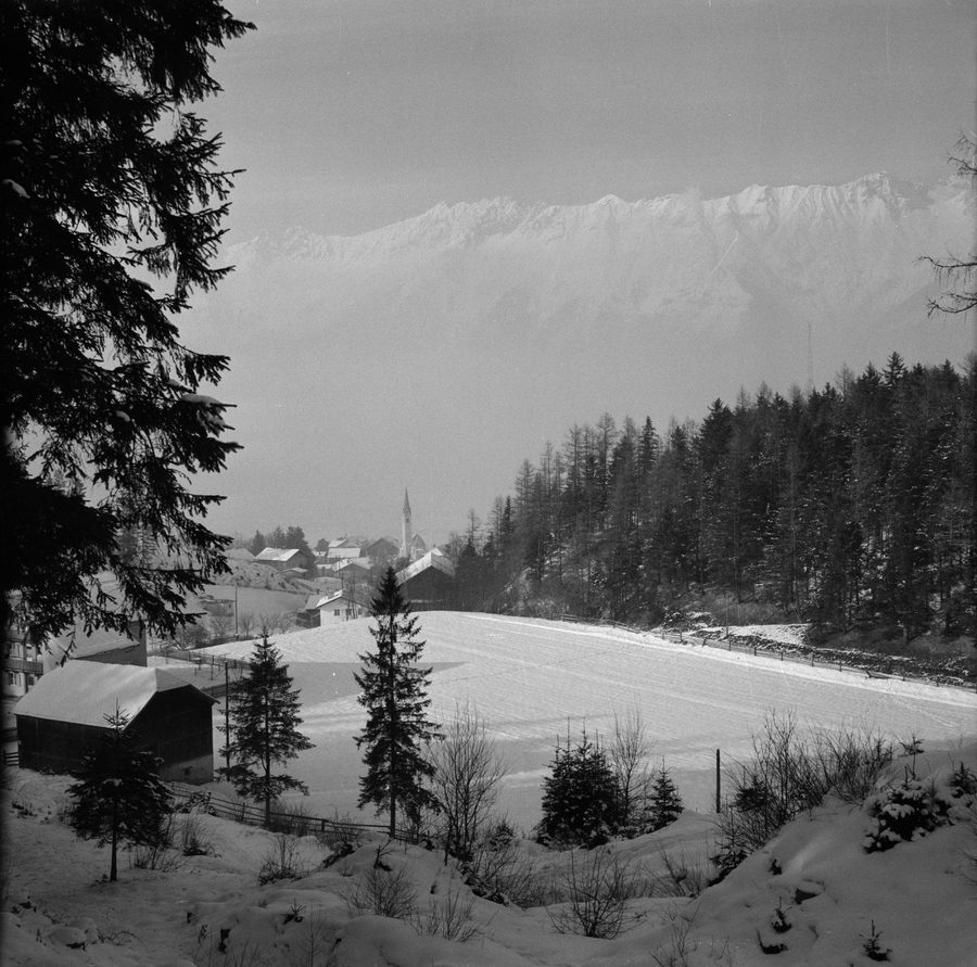 Aldrans in Tirolo come villaggio innevato davanti a un paesaggio alpino di montagna