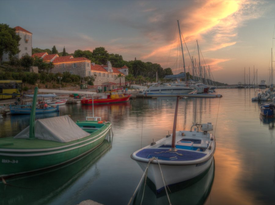Porto di Maslinica sull’isola di Šolta al tramonto con barca da pesca e paesaggio costiero