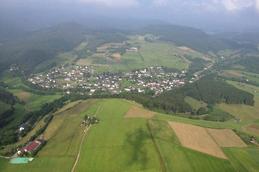 Veduta aerea di Hallenberg-Liesen con terreno aperto e pendii boscosi sullo sfondo