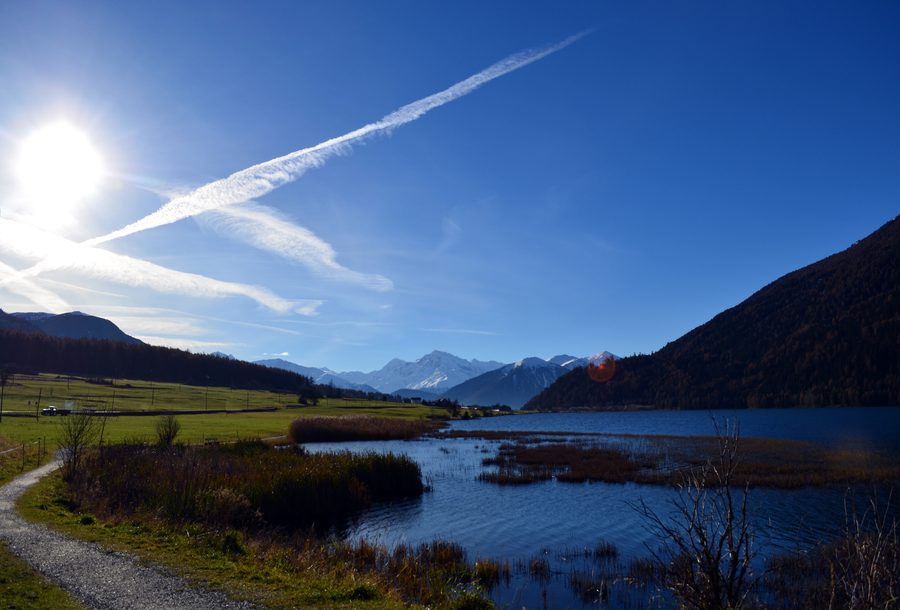 Lago di Resia circondato da montagne alpine innevate in Alto Adige