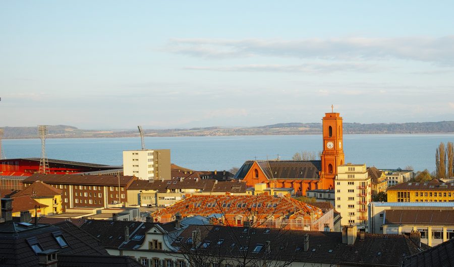 Parte di Neuchâtel con la chiesa Notre-Dame-de-l’Assomption e il lago di Neuchâtel alla luce della sera