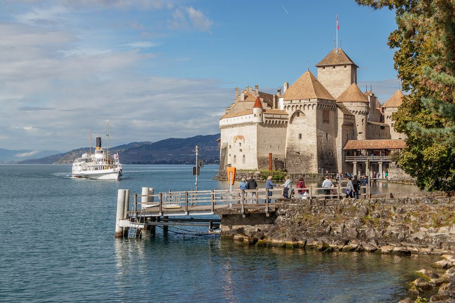 Il Castello di Chillon sulla riva del Lago Lemano mentre si avvicina un battello a vapore storico.