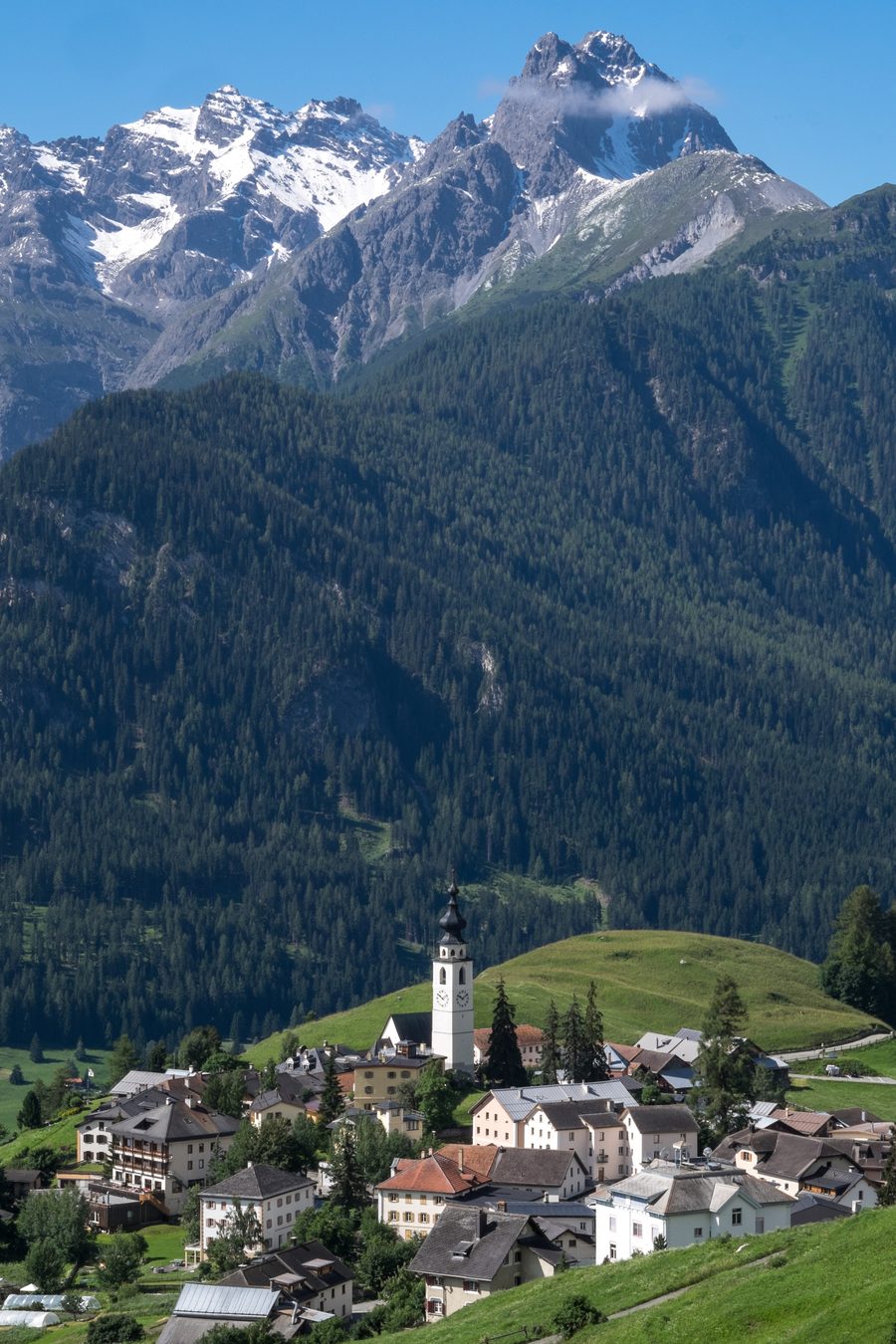 Ftan con case del villaggio, chiesa e panorama alpino nell’Engadina Bassa